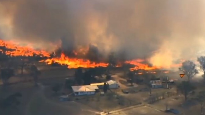 An aerial view of a bushfire burning close to homes.