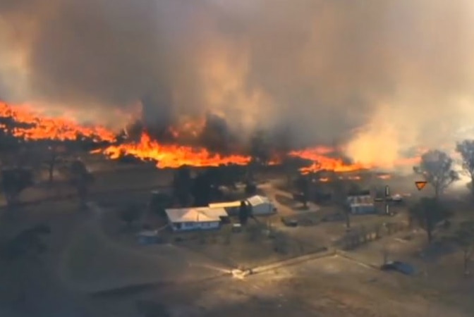 An aerial view of a bushfire burning close to homes.