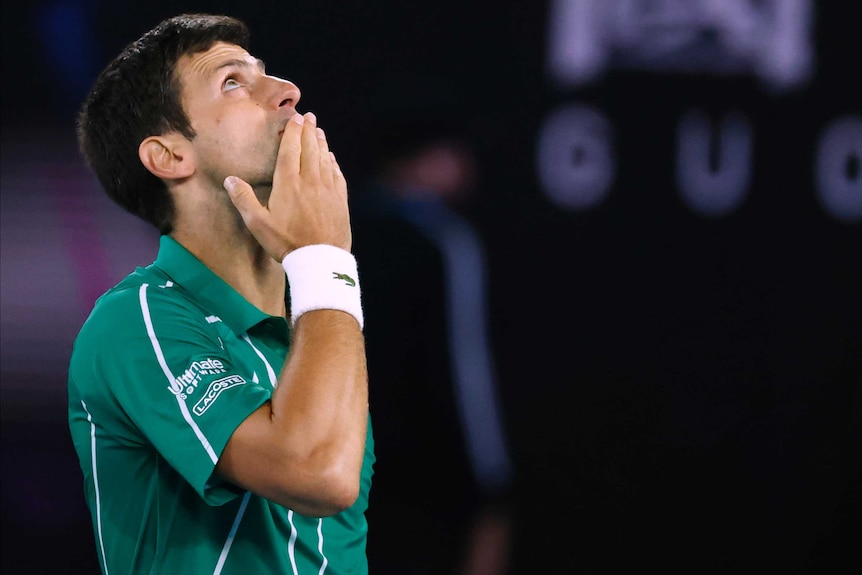 A male tennis player puts a finger to his mouth as he looks to the sky at the Australian Open.