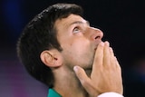 A male tennis player puts a finger to his mouth as he looks to the sky at the Australian Open.