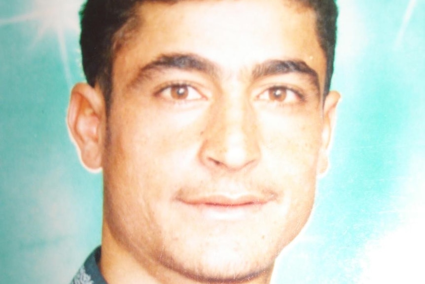 Portrait of a young man in a blue shirt in front of a green background.