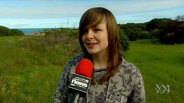 Teenage girl stands outdoors with BTN microphone