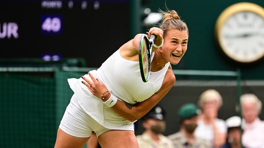 A female tennis player serves at Wimbledon.