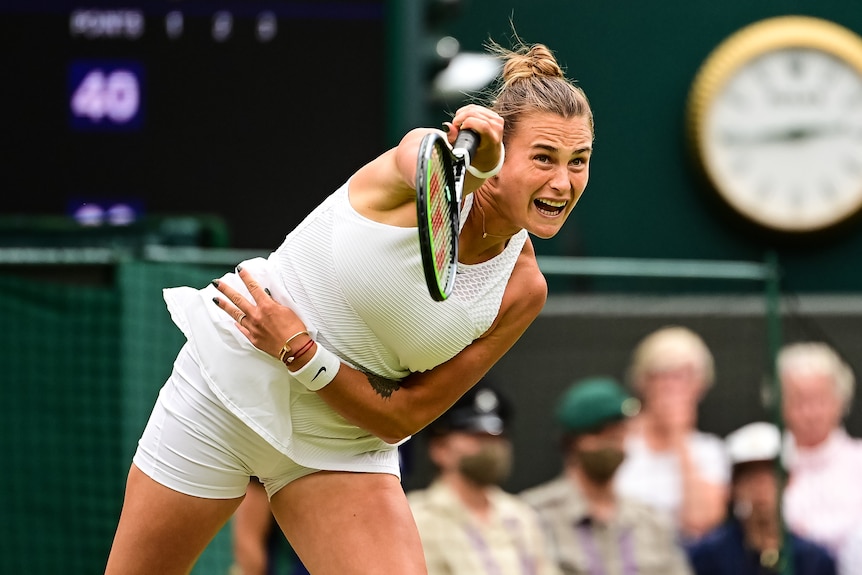 A female tennis player serves at Wimbledon.