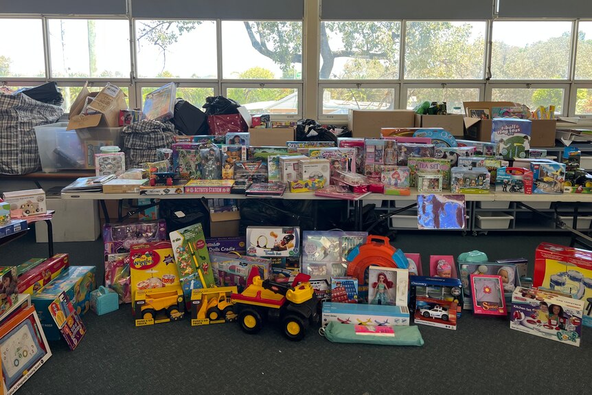 Toys and presents sit on tables and the floor after they have been donated.