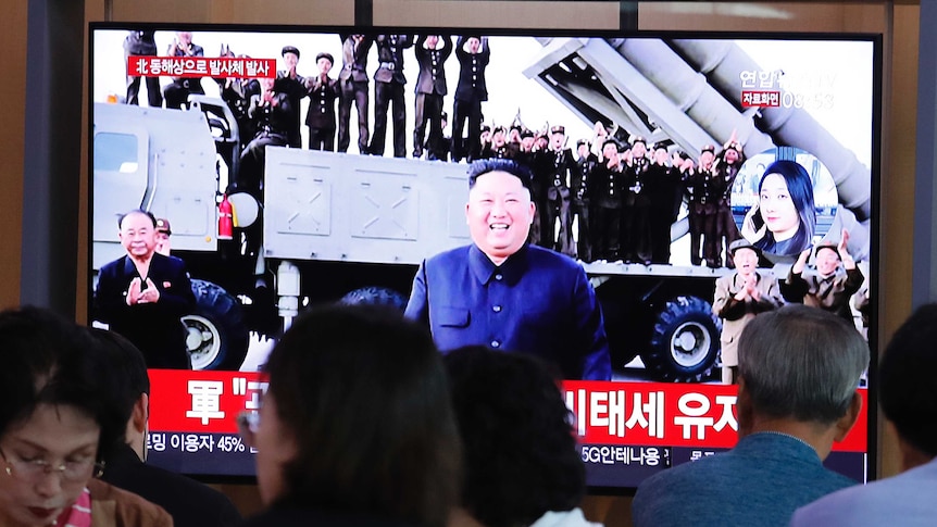 People watch a TV showing a file image of North Korean leader Kim Jong Un during a news program