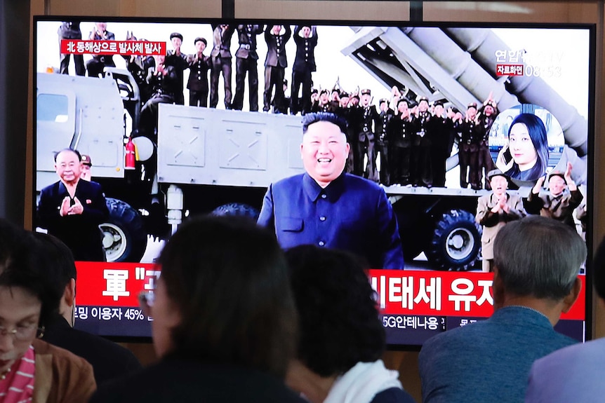 People watch a TV showing a file image of North Korean leader Kim Jong Un during a news program