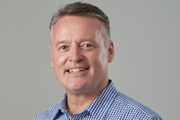 A headshot of a smiling man with short, greying hair.