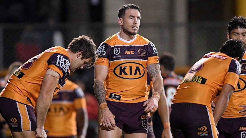 Darius Boyd stands between two teammates who are on their haunches with a resigned expression on his face