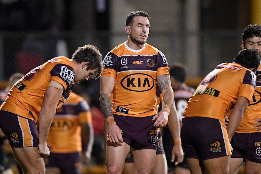 Darius Boyd stands between two teammates who are on their haunches with a resigned expression on his face