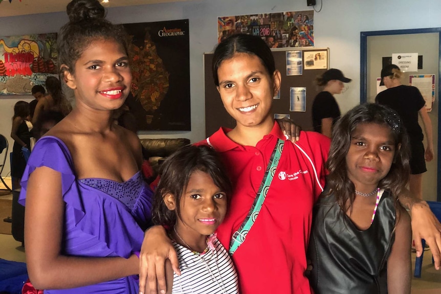 A young Aboriginal woman with a teenage Aboriginal girl and two, younger Aboriginal girls smiling at camera