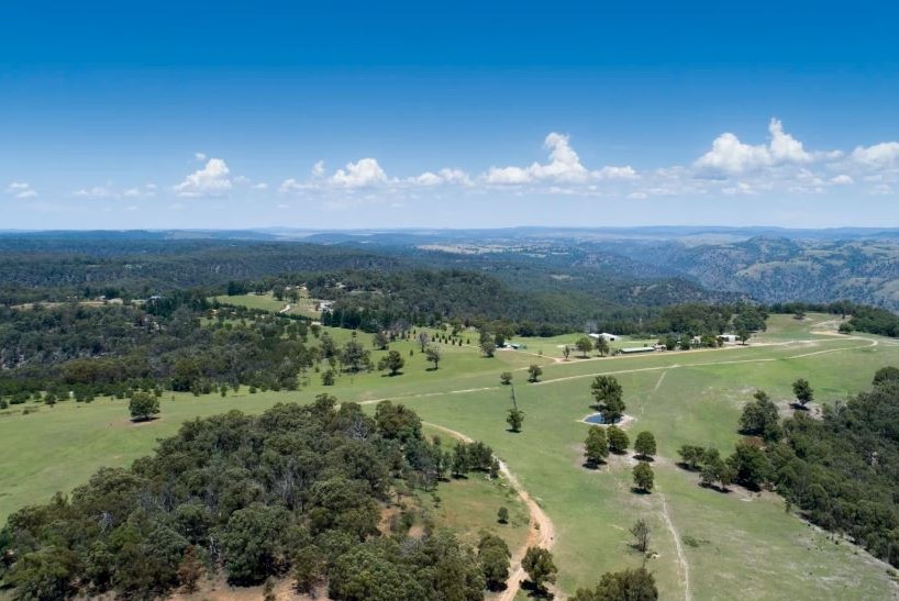 Aerial shot of farm and bushland in the background.