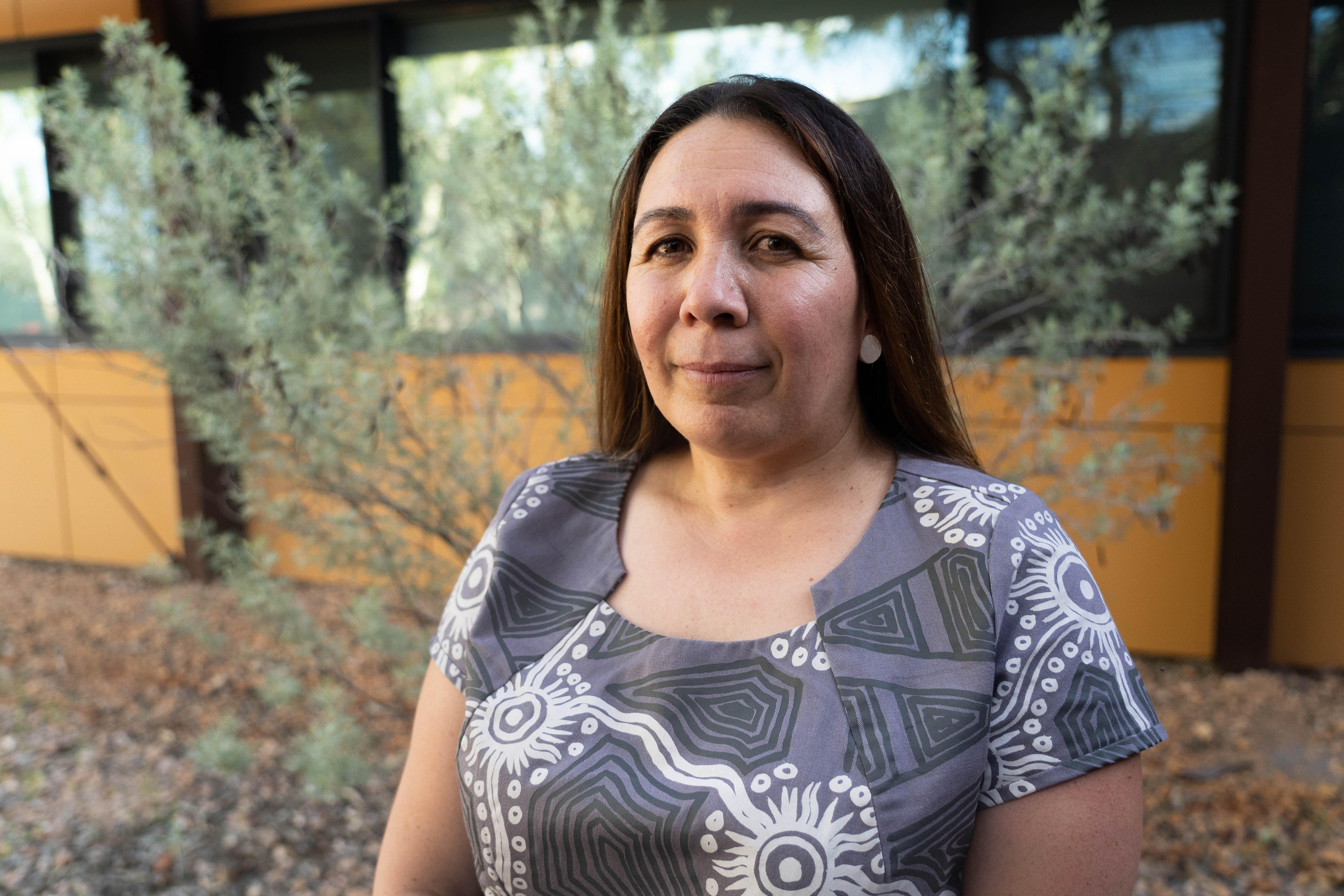 A middle-aged Indigenous woman looks at the camera with a slight smile