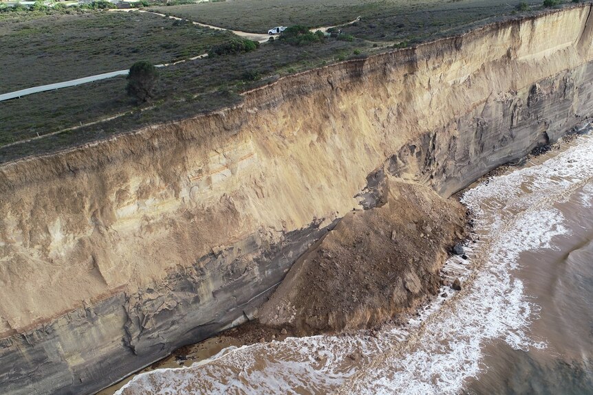 An aerial shot of a landslip of a cliff on a beach.