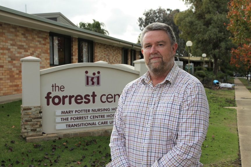A man stands in front of a sign which reads 'the forrest centre'