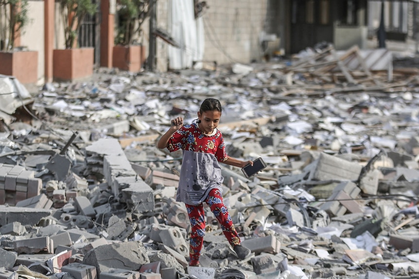 A girl walks amongst rubble in Gaza.