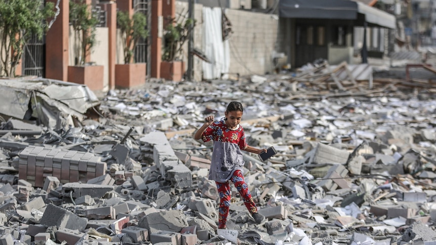 A girl walks amongst rubble in Gaza.