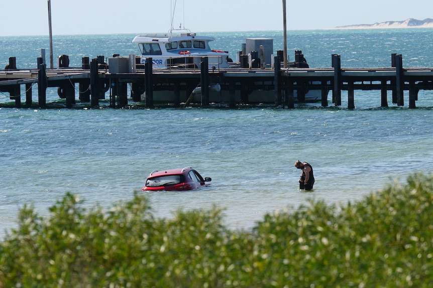 A car submerged in the ocean with just the roof showing