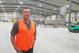 Man in an orange high-vis vest stands on a factory floor