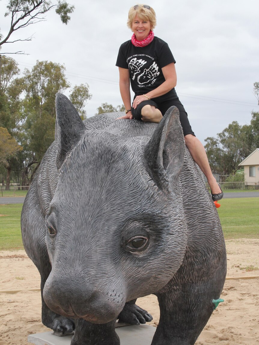 A woman sits on the top of a large wombat statue