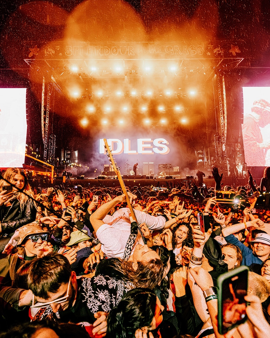 Manipulated image of Idles performing live with the stage in the top half and the guitarist crowdsurfing in the lower half