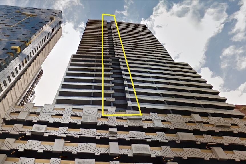 A photo of an apartment building with a vertical yellow rectangle highlighting a strip of cladding material.