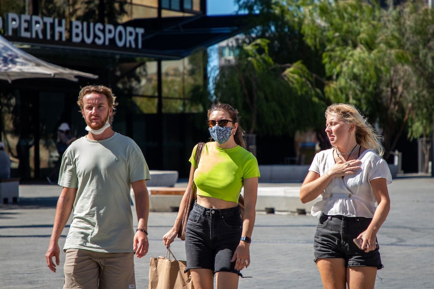 Two women and a man walk in Perth, two of them with masks