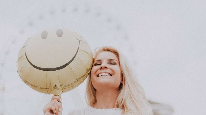 Woman smiling while holding a smiling balloon