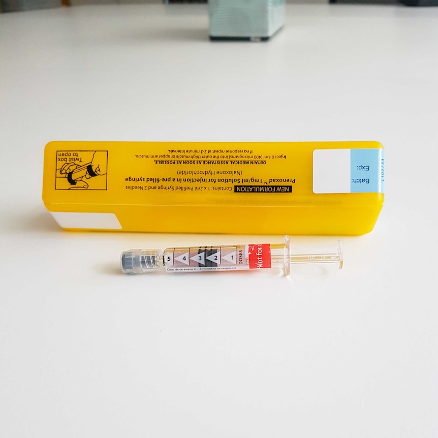A Naloxone kit including a needle and a yellow plastic case.