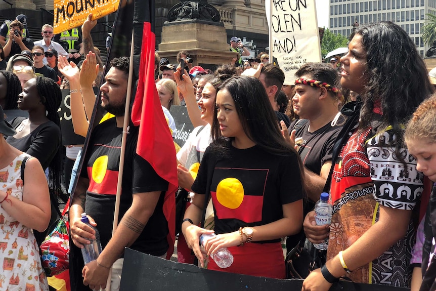 Protesters carrying Aboriginal flags march outside Victoria's Parliament House in Melbourne.