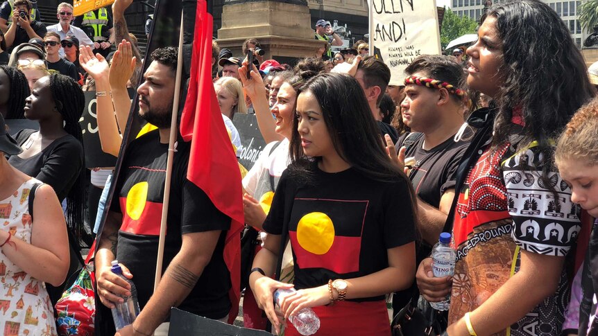Protesters carrying Aboriginal flags march outside Victoria's Parliament House in Melbourne.