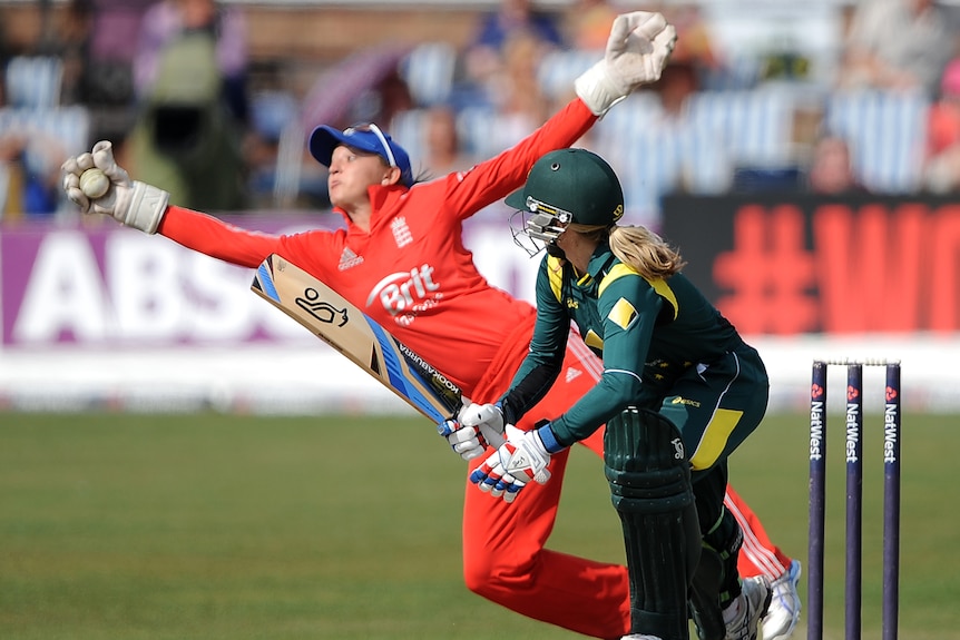 Sarah Taylor stretches to catch the ball while Jodie Fields looks on.