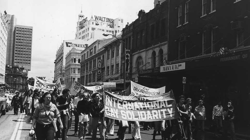 People with placards march through the street in this black and white picture.