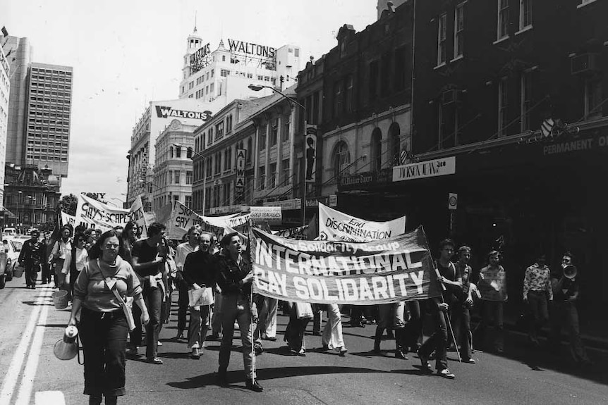 People with placards march through the street in this black and white picture.