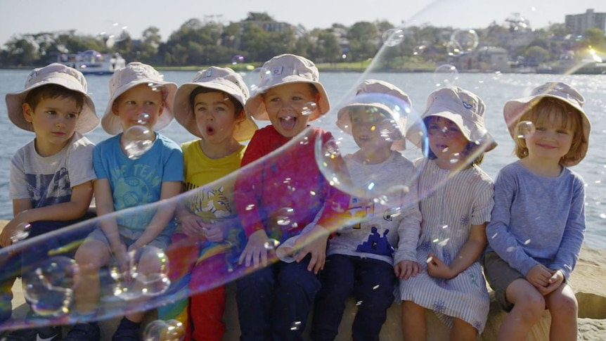 A group of kids looking at some bubbles