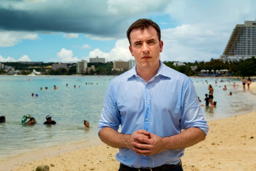 Andrew Greene in sweat soaked shirt reporting from beach in Guam.