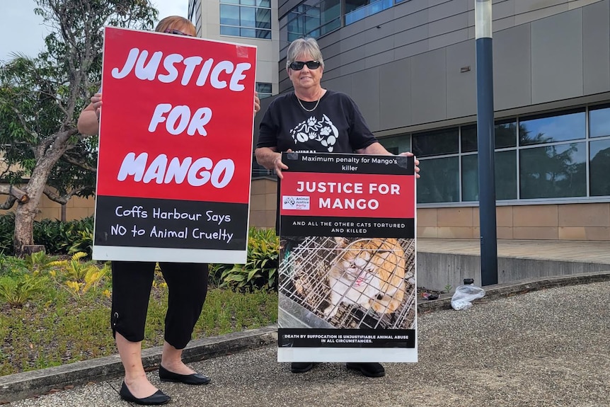 Two women hold large placards, one featuring a picture of a ginger cat, that say "Justice for Mango".