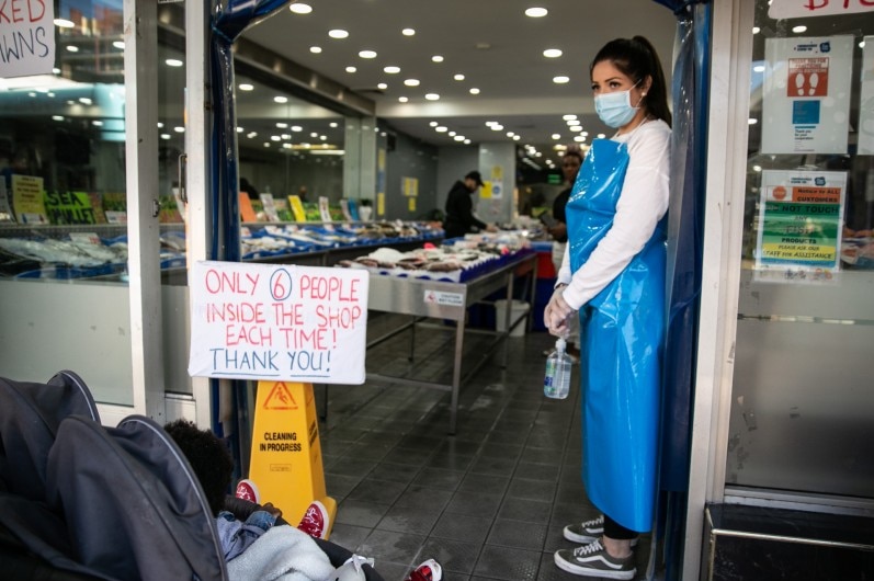 A worker monitors people entering the Smart St Fish Market.