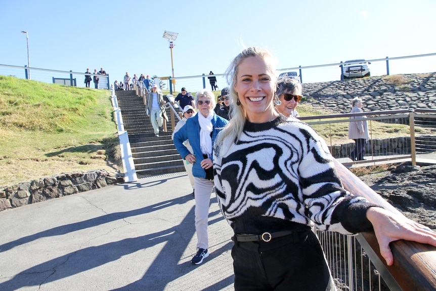 A woman smiles whilst standing on the stairs at Kiama Blowhole.