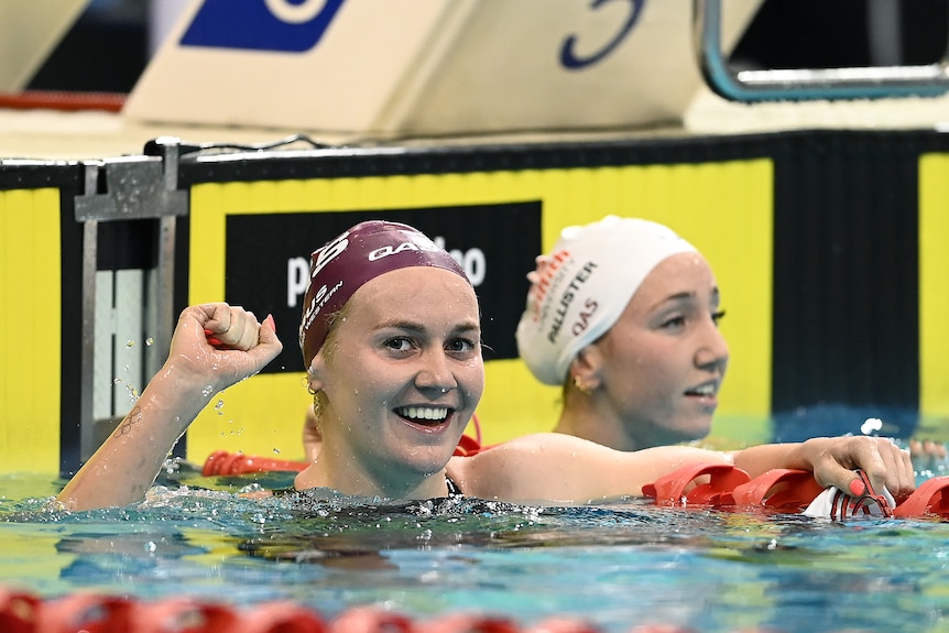 Ariarne Titmus smiles and clenches her fist in the water