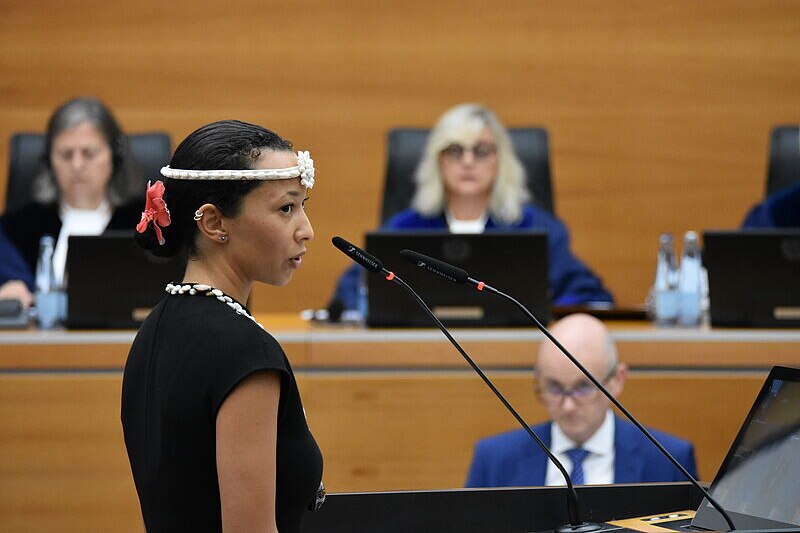 A woman waering white traditional headband speaks into microphones at court.