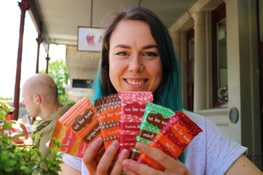 A woman holding up six energy bars.