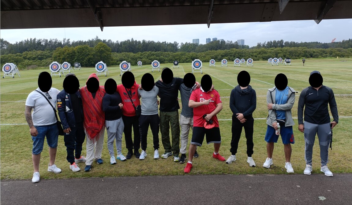 A group of men taking photo together in a archery field