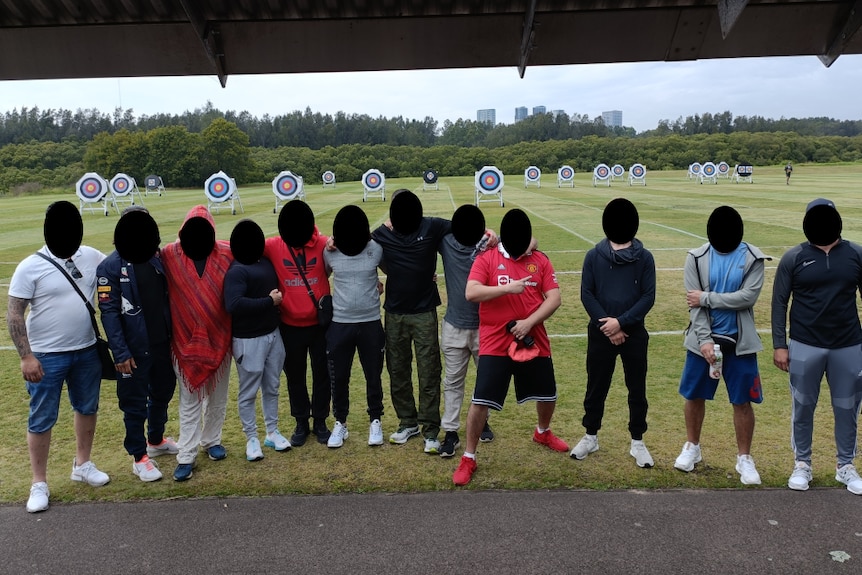 A group of men taking photo together in a archery field