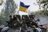 Ukrainian servicemen ride on an armoured vehicle