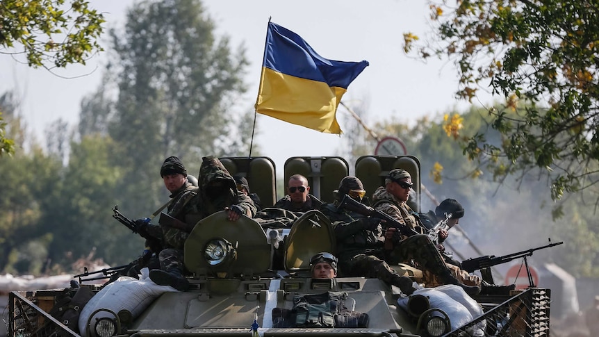 Ukrainian servicemen ride on an armoured vehicle