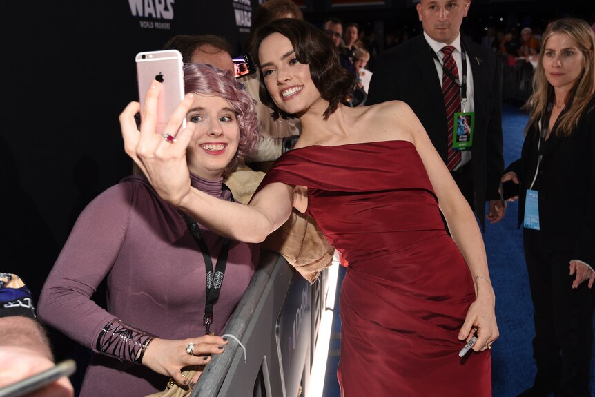 Daisy Ridley, right, takes a selfie with a fan