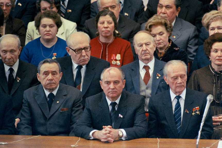 戈尔巴乔夫坐在一张桌子的中央，周围都是西装革履的男女。