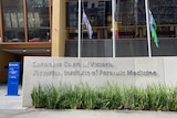 The Coroners Court of Victoria sign in front of the Australian, Aboriginal, and Torres Strait Islander flags.