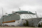 The freedom of the seas cruise ship towers above the dock it is anchored to. It is white with aqua accented windows.